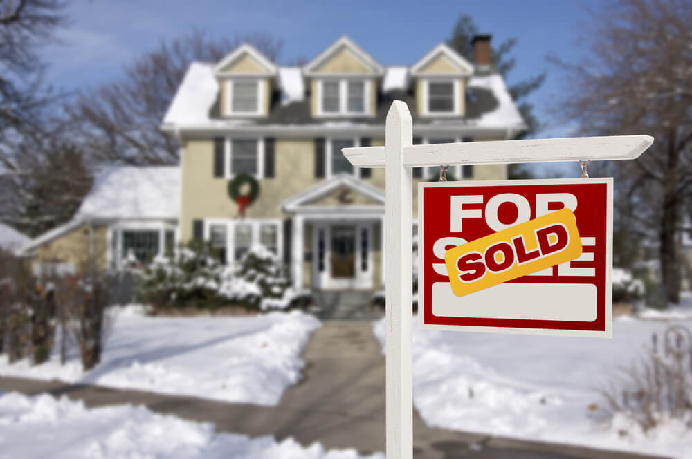 sold sign in front of a home during the winter with snow on the ground